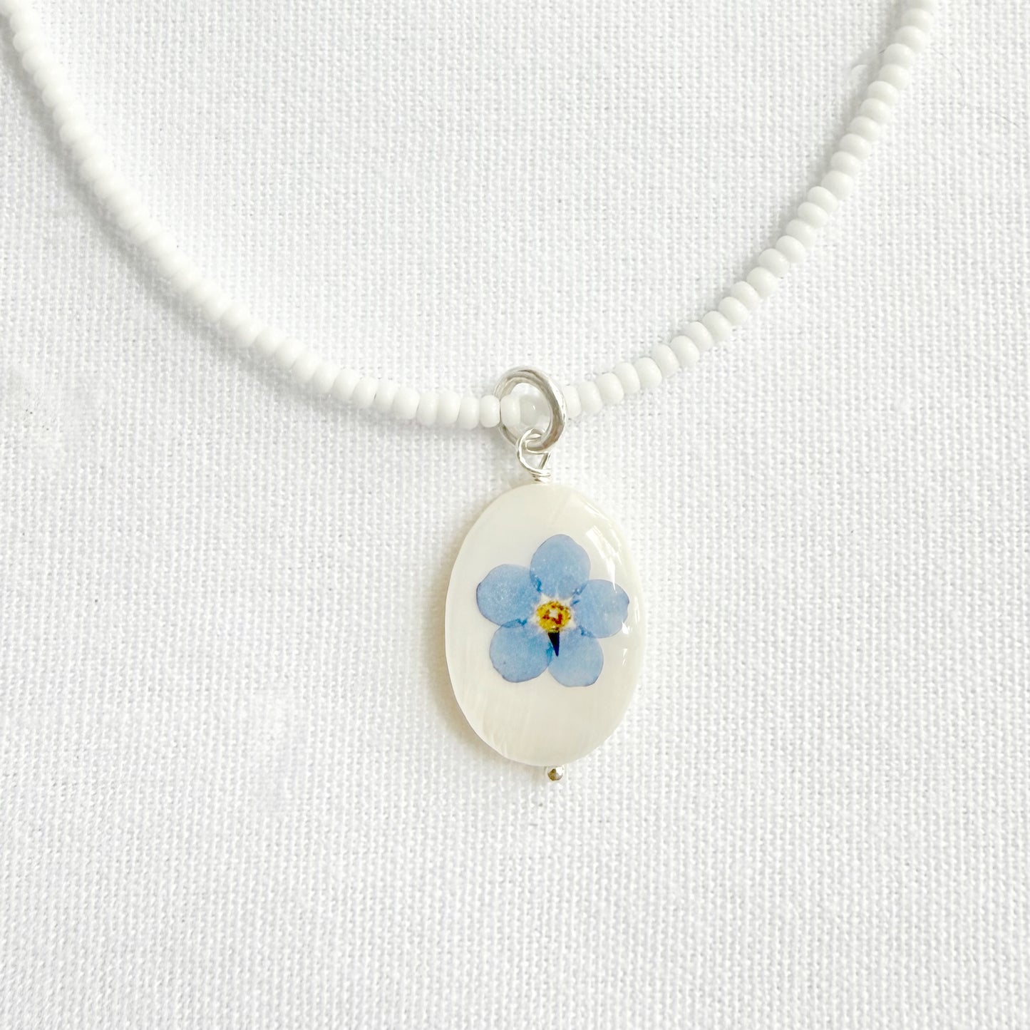 White glass beaded necklace with forget-me-not oval pendant